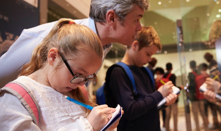 stock image of children taking notes in museum