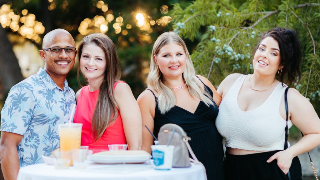 four people smiling with cocktails in the garden