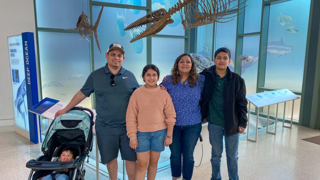 Family of 5 standing in front of deep sea fossils.