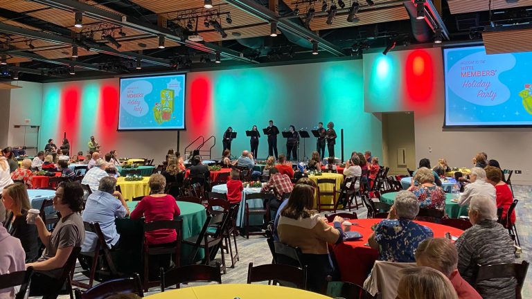 ballroom filled with people at tables and handbell performance on stage.